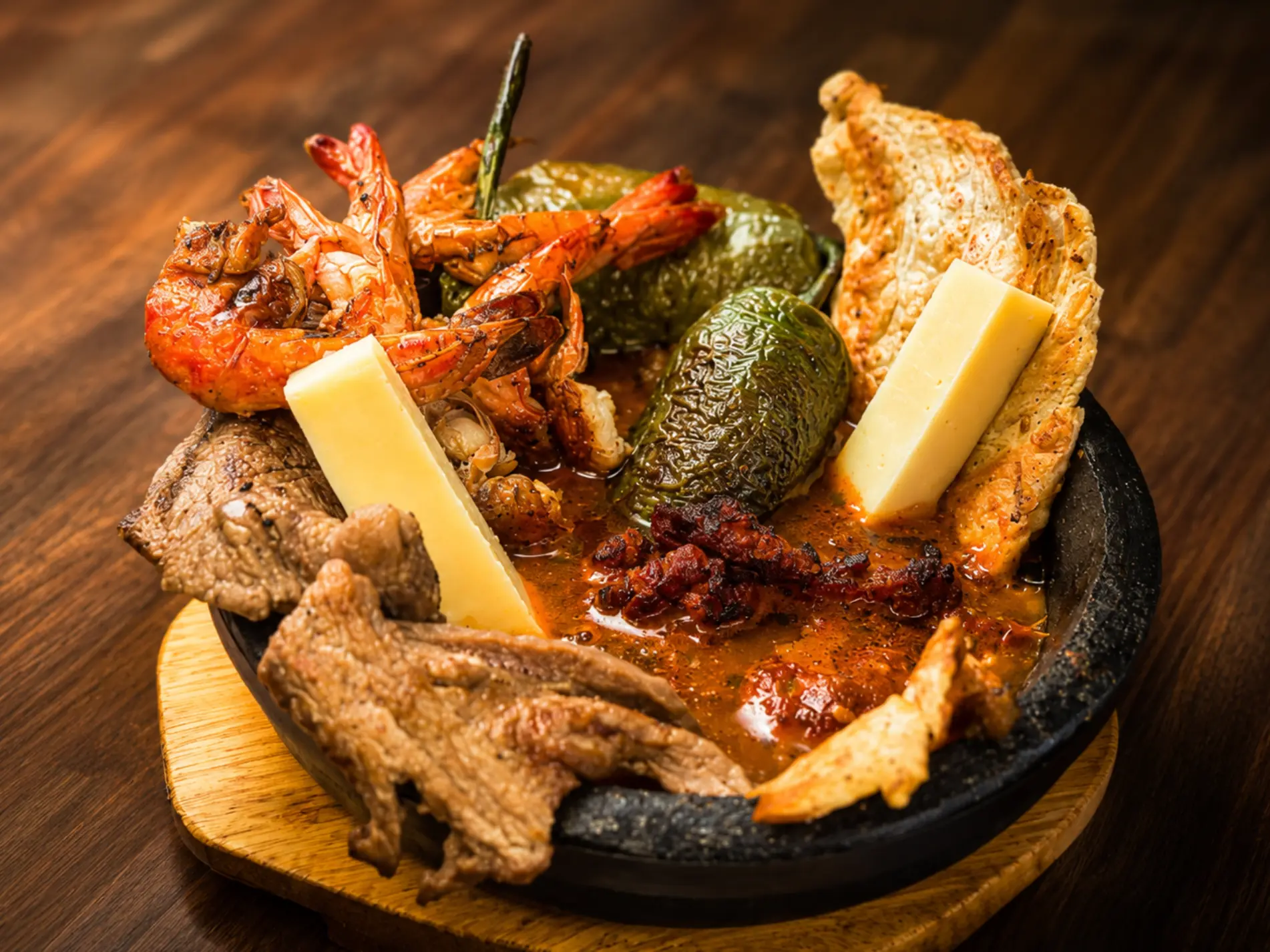 Sizzling molcajete with shrimp, steak, chorizo and cheese