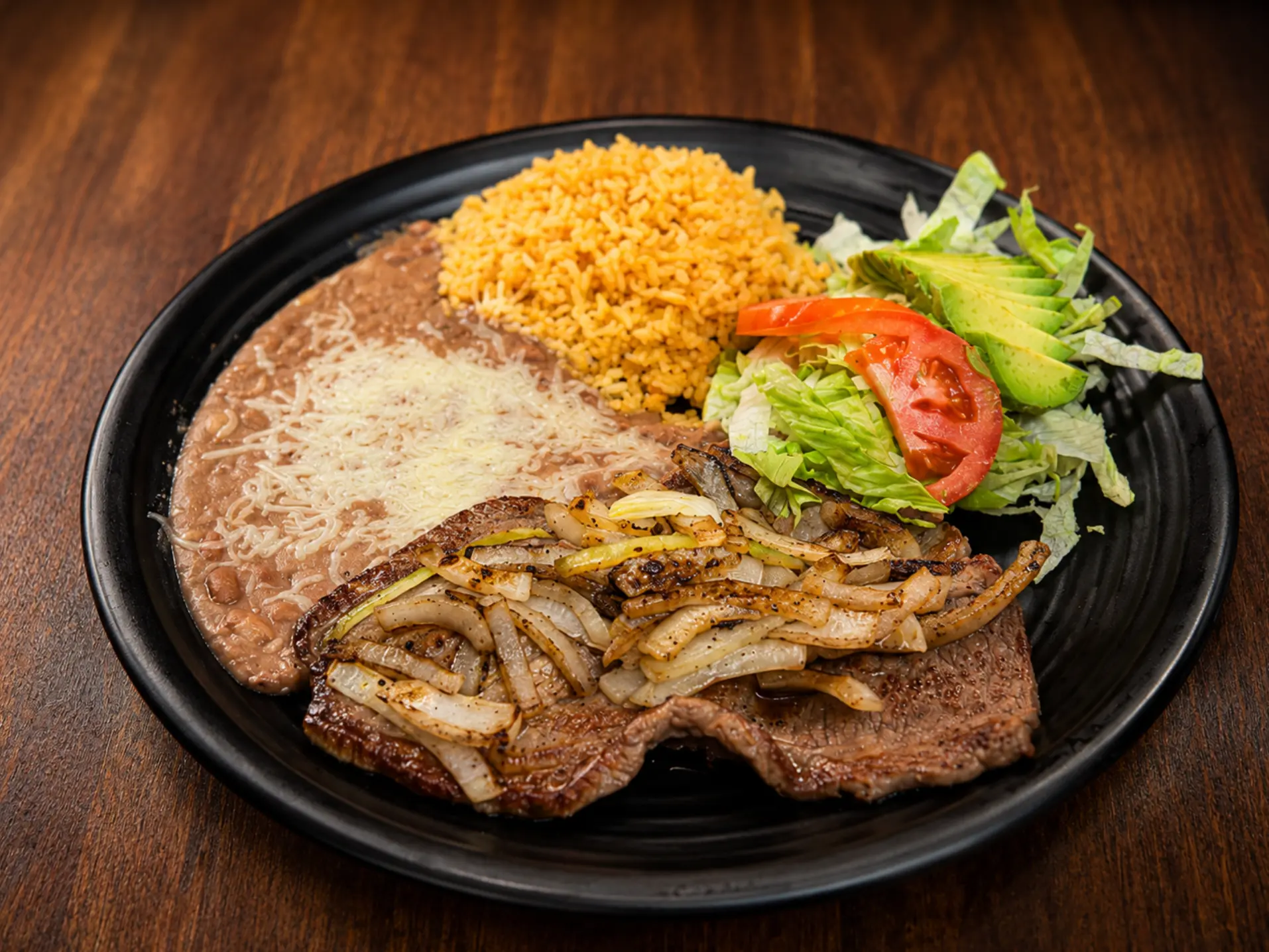 Bistec encebollado with rice, beans and salad
