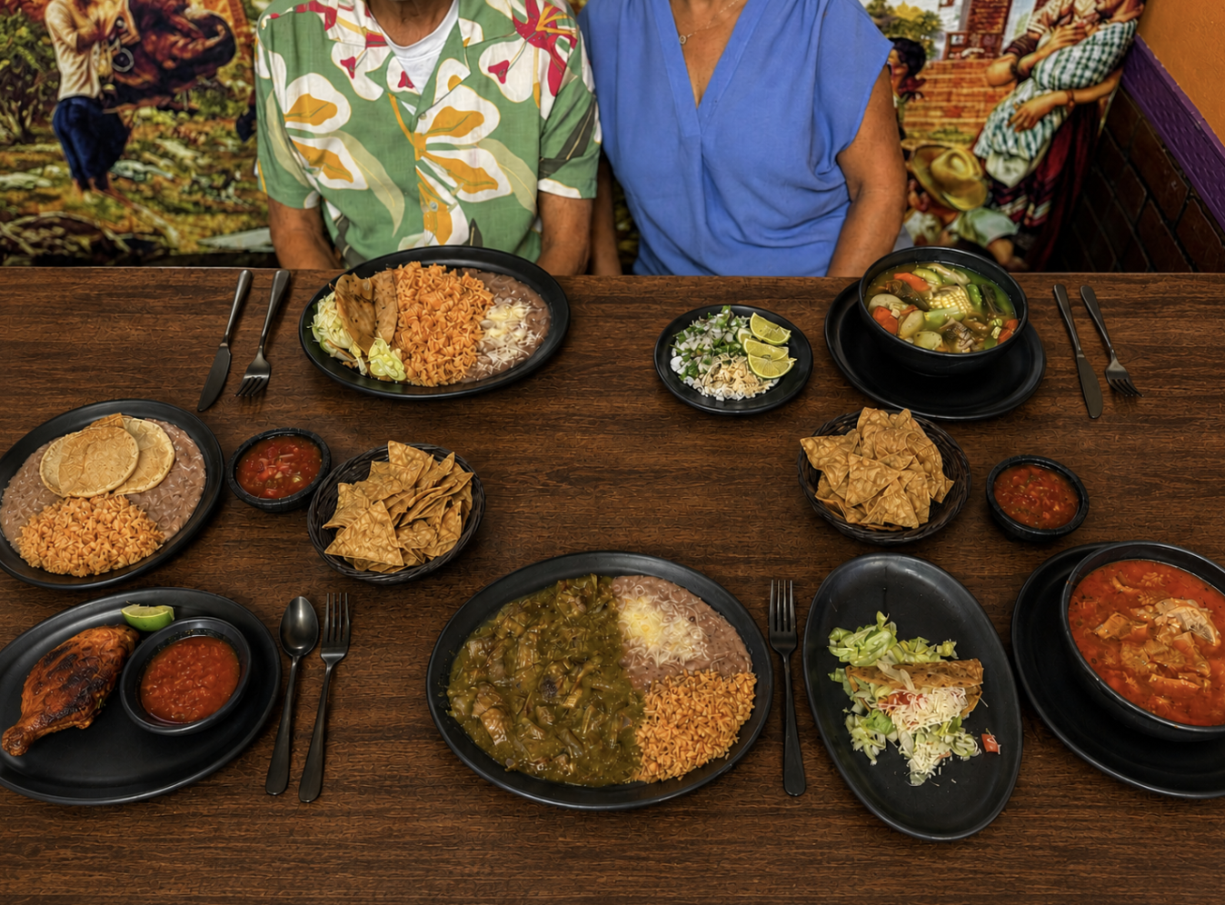 Two guests at El Caporal with a full spread of Mexican dishes across the table